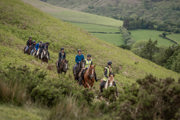 An image of single file riders on horseback winding up, down and through the Brecon country terrain.