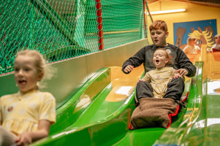 An image of two children whooshing down an indoor slide together at Cantref Adventure Farm.