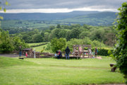 A landscape wide shot of the sand and water outdoor play area at Cantref Adventure Farm, with a lovely view behind.
