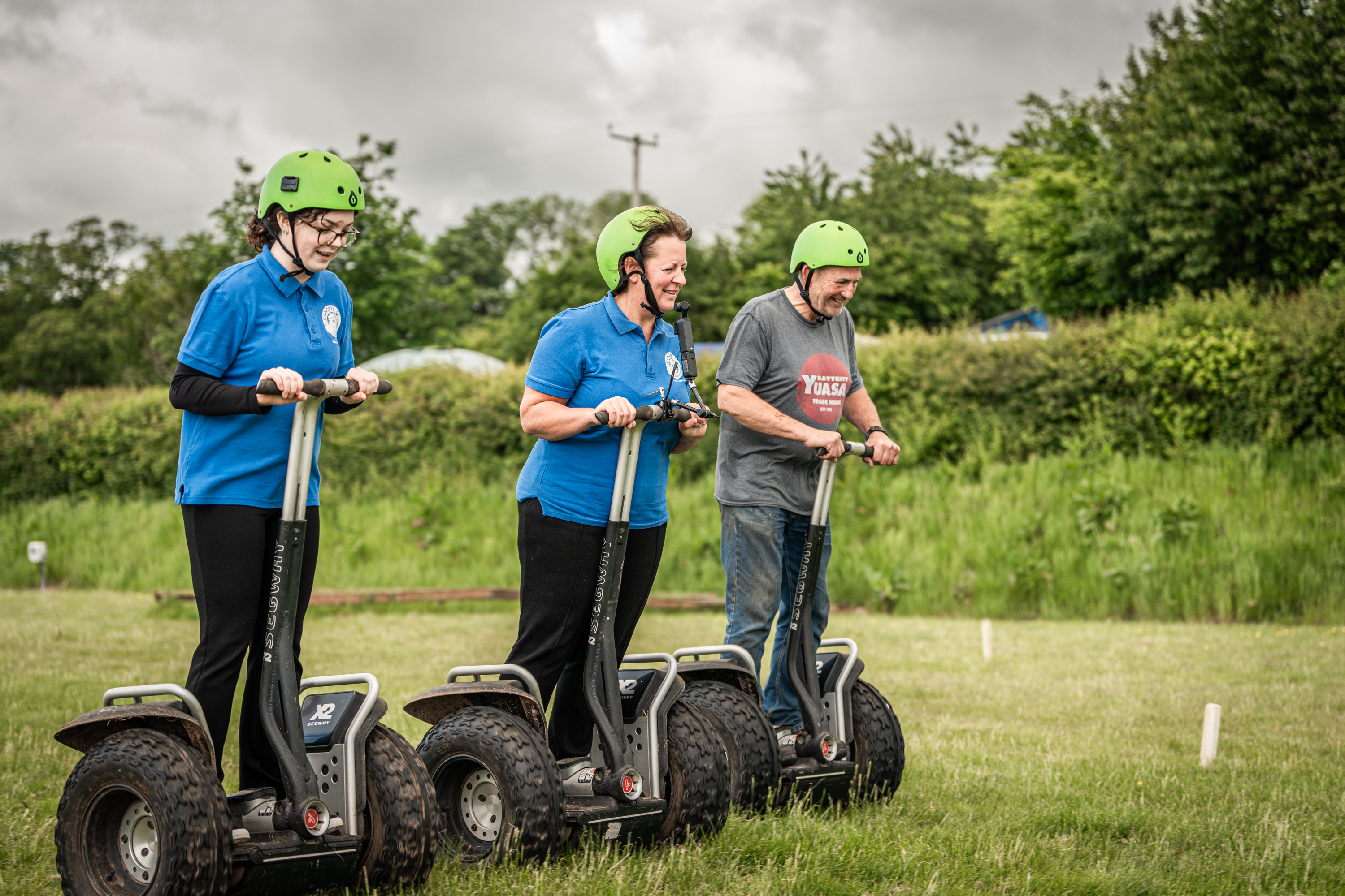 An image of a group of three using Segways on the grass practice field.