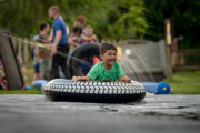 An image of a boy on an inflatable doughnut, sliding down a soapy slide, with a massive smile on his face.