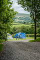 An image of two tents pitched on luscious green grass, with a wonderful view of Brecon all around.