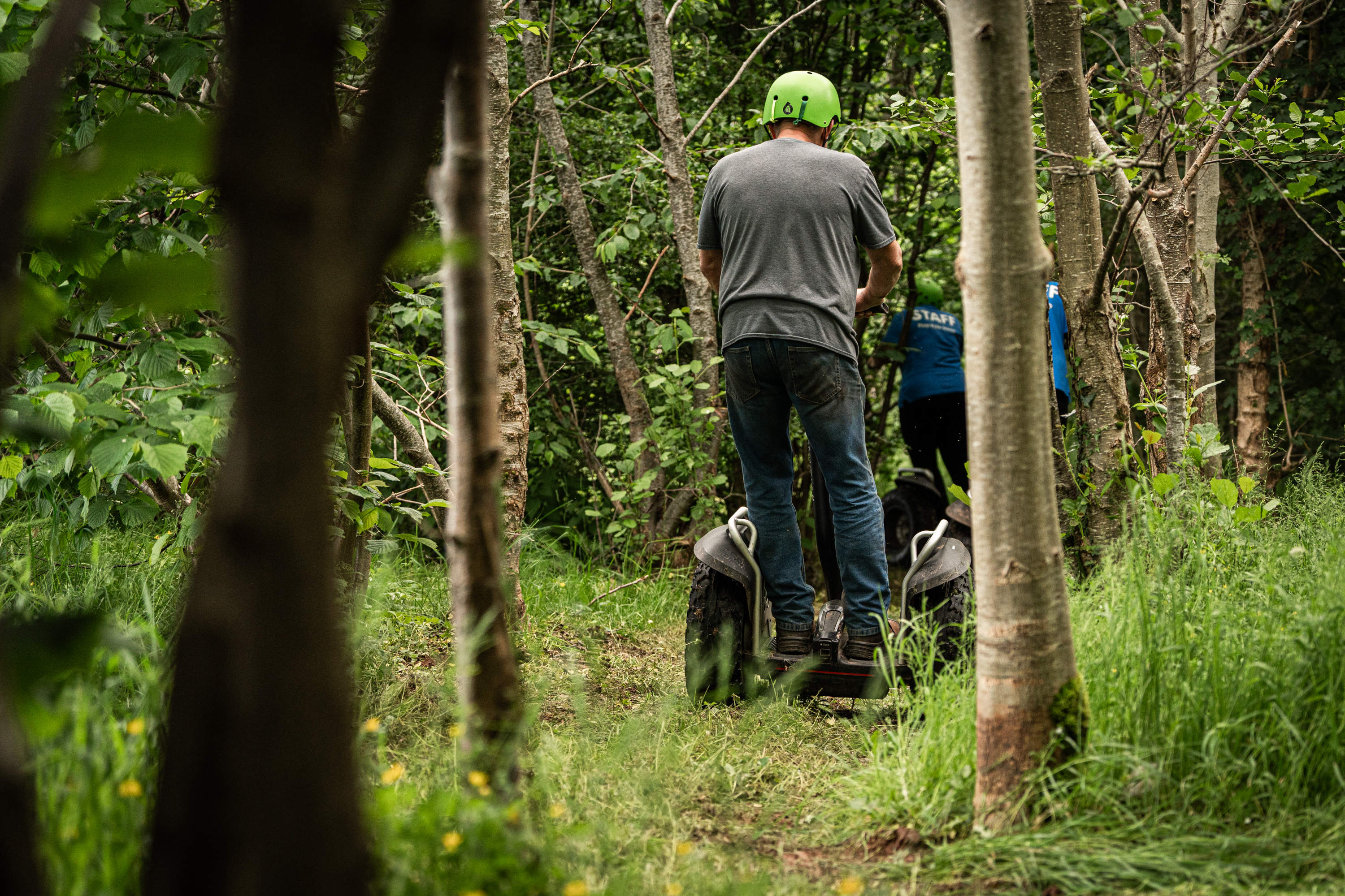 An image of a man on a Segway going down a path through the woods.